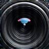 A camera lens focused on a subject, representing visual content creation.
